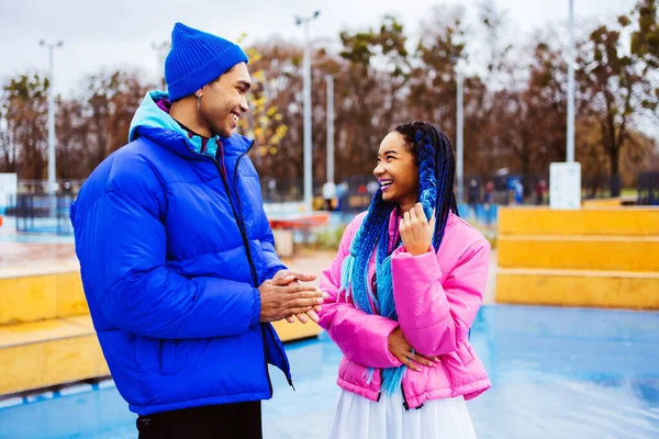Multiracial young couple of lovers dating outdoors in winter, wearing winter jackets and having fun - Multiethnic millennials bonding in a urban area, concepts about youth and social releationships