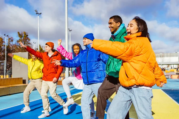 Multiracial group of young happy friends meeting outdoors in winter, wearing winter jackets and having fun - Multiethnic millennials bonding in a urban area, concepts about youth and social releationships