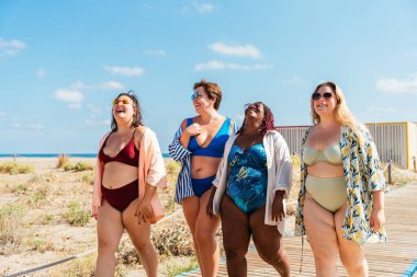 Group of beautiful plus size women with swimwear bonding and having fun at the beach - Group of curvy female friends enjoying summertime at the sea, concepts about body acceptance, body positive and self confidence