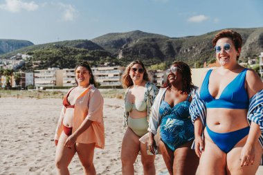 Group of beautiful plus size women with swimwear bonding and having fun at the beach - Group of curvy female friends enjoying summertime at the sea, concepts about body acceptance, body positive and self confidence