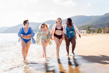 Group of beautiful plus size women with swimwear bonding and having fun at the beach - Group of curvy female friends enjoying summertime at the sea, concepts about body acceptance, body positive and self confidence