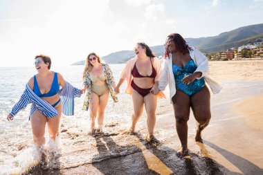 Group of beautiful plus size women with swimwear bonding and having fun at the beach - Group of curvy female friends enjoying summertime at the sea, concepts about body acceptance, body positive and self confidence