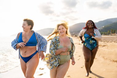 Group of beautiful plus size women with swimwear bonding and having fun at the beach - Group of curvy female friends enjoying summertime at the sea, concepts about body acceptance, body positive and self confidence