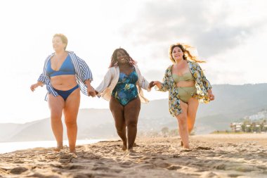 Group of beautiful plus size women with swimwear bonding and having fun at the beach - Group of curvy female friends enjoying summertime at the sea, concepts about body acceptance, body positive and self confidence