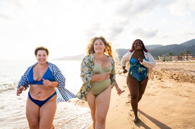 Group of beautiful plus size women with swimwear bonding and having fun at the beach - Group of curvy female friends enjoying summertime at the sea, concepts about body acceptance, body positive and self confidence