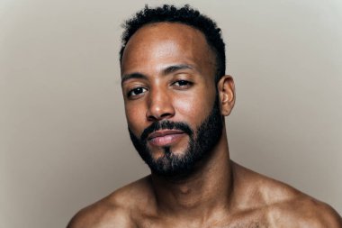 Tenine bakan genç bir adamın görüntüsü. Güzellik stüdyosu cilt bakımı ve kişisel hijyen ürünleri hakkında çekim yapıyor..