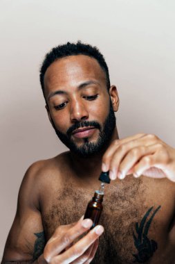 Tenine bakan genç bir adamın görüntüsü. Güzellik stüdyosu cilt bakımı ve kişisel hijyen ürünleri hakkında çekim yapıyor..