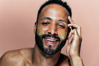 Tenine bakan genç bir adamın görüntüsü. Güzellik stüdyosu cilt bakımı ve kişisel hijyen ürünleri hakkında çekim yapıyor..