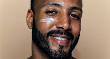 Tenine bakan genç bir adamın görüntüsü. Güzellik stüdyosu cilt bakımı ve kişisel hijyen ürünleri hakkında çekim yapıyor..