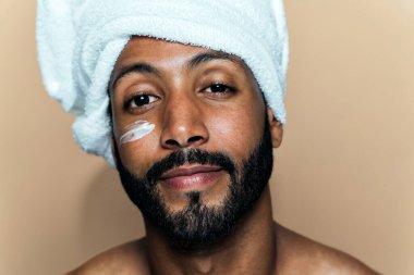 Tenine bakan genç bir adamın görüntüsü. Güzellik stüdyosu cilt bakımı ve kişisel hijyen ürünleri hakkında çekim yapıyor..