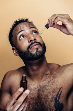 Tenine bakan genç bir adamın görüntüsü. Güzellik stüdyosu cilt bakımı ve kişisel hijyen ürünleri hakkında çekim yapıyor..