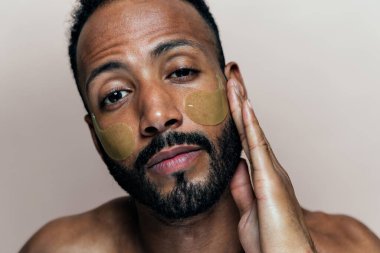 Tenine bakan genç bir adamın görüntüsü. Güzellik stüdyosu cilt bakımı ve kişisel hijyen ürünleri hakkında çekim yapıyor..