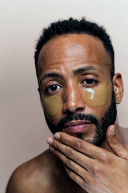 Tenine bakan genç bir adamın görüntüsü. Güzellik stüdyosu cilt bakımı ve kişisel hijyen ürünleri hakkında çekim yapıyor..