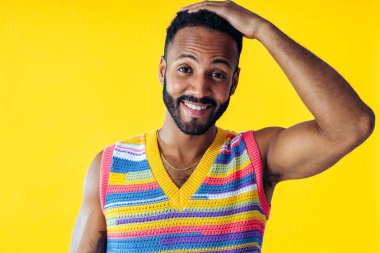 Renkli kıyafetler giyen, renkli arka planda poz veren yakışıklı bir genç resmi. Tasasız, moda ve yaşam tarzı kavramları