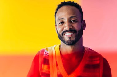 Renkli kıyafetler giyen, renkli arka planda poz veren yakışıklı bir genç resmi. Tasasız, moda ve yaşam tarzı kavramları