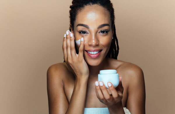 Красивая женщина делает кожу и косметические процедуры для лица. Студийная съемка с акцентом на концепции косметики и ухода за кожей