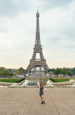 Beautiful young woman visiting paris and the eiffel tower. Parisian girl with red hat and fashionable clothes having fun in the city center and landmarks area