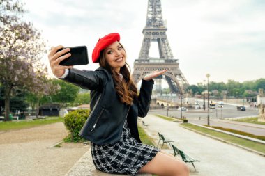 Beautiful young woman visiting paris and the eiffel tower. Parisian girl with red hat and fashionable clothes having fun in the city center and landmarks area