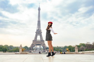 Beautiful young woman visiting paris and the eiffel tower. Parisian girl with red hat and fashionable clothes having fun in the city center and landmarks area
