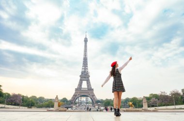 Beautiful young woman visiting paris and the eiffel tower. Parisian girl with red hat and fashionable clothes having fun in the city center and landmarks area