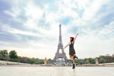 Beautiful young woman visiting paris and the eiffel tower. Parisian girl with red hat and fashionable clothes having fun in the city center and landmarks area