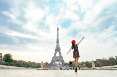 Beautiful young woman visiting paris and the eiffel tower. Parisian girl with red hat and fashionable clothes having fun in the city center and landmarks area