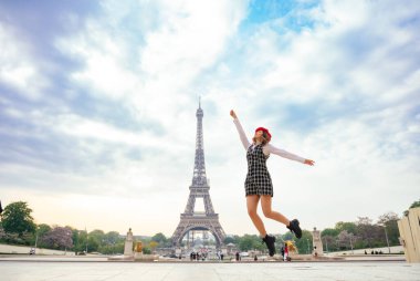 Beautiful young woman visiting paris and the eiffel tower. Parisian girl with red hat and fashionable clothes having fun in the city center and landmarks area