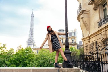 Beautiful young woman visiting paris and the eiffel tower. Parisian girl with red hat and fashionable clothes having fun in the city center and landmarks area