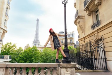 Beautiful young woman visiting paris and the eiffel tower. Parisian girl with red hat and fashionable clothes having fun in the city center and landmarks area