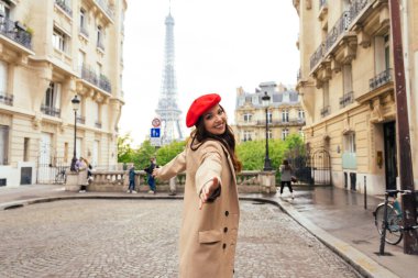 Beautiful young woman visiting paris and the eiffel tower. Parisian girl with red hat and fashionable clothes having fun in the city center and landmarks area