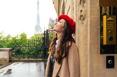 Beautiful young woman visiting paris and the eiffel tower. Parisian girl with red hat and fashionable clothes having fun in the city center and landmarks area