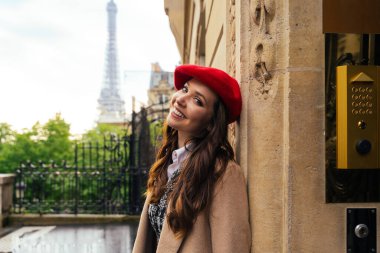 Beautiful young woman visiting paris and the eiffel tower. Parisian girl with red hat and fashionable clothes having fun in the city center and landmarks area