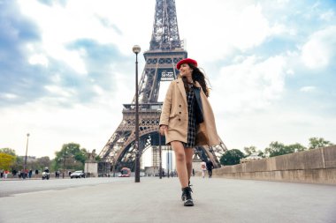 Beautiful young woman visiting paris and the eiffel tower. Parisian girl with red hat and fashionable clothes having fun in the city center and landmarks area