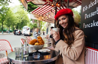 Beautiful young woman visiting paris and the eiffel tower. Parisian girl with red hat and fashionable clothes having fun in the city center and landmarks area
