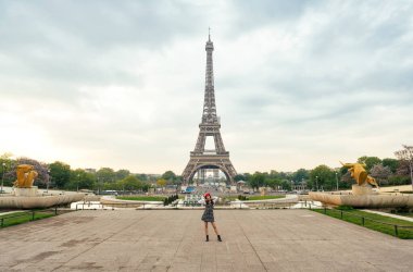 Beautiful young woman visiting paris and the eiffel tower. Parisian girl with red hat and fashionable clothes having fun in the city center and landmarks area