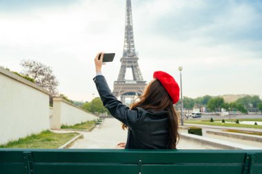 Beautiful young woman visiting paris and the eiffel tower. Parisian girl with red hat and fashionable clothes having fun in the city center and landmarks area