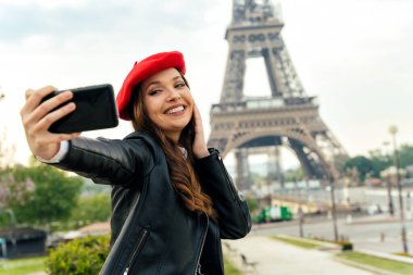Beautiful young woman visiting paris and the eiffel tower. Parisian girl with red hat and fashionable clothes having fun in the city center and landmarks area