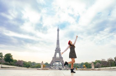 Beautiful young woman visiting paris and the eiffel tower. Parisian girl with red hat and fashionable clothes having fun in the city center and landmarks area