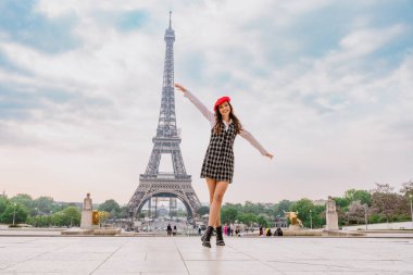 Beautiful young woman visiting paris and the eiffel tower. Parisian girl with red hat and fashionable clothes having fun in the city center and landmarks area