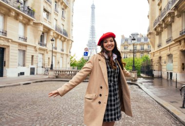 Beautiful young woman visiting paris and the eiffel tower. Parisian girl with red hat and fashionable clothes having fun in the city center and landmarks area