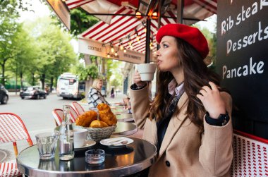 Beautiful young woman visiting paris and the eiffel tower. Parisian girl with red hat and fashionable clothes having fun in the city center and landmarks area