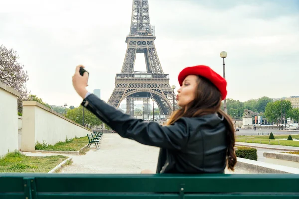 Beautiful young woman visiting paris and the eiffel tower. Parisian girl with red hat and fashionable clothes having fun in the city center and landmarks area