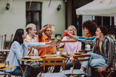 Multiracial young people together meeting and having party in a restaurant - Group of friends with mixed races having fun celebrating in a bar- Friendship and lifestyle concepts