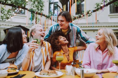Multiracial young people together meeting and having party in a restaurant - Group of friends with mixed races having fun celebrating in a bar- Friendship and lifestyle concepts