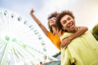 Multiracial young couple of lovers dating at theferry wheel in the amusement park - People with mixed races having fun outdoors in the city- Friendship, releationship and lifestyle concepts
