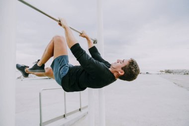 Sportive and athletic man doing functional training exercise at the outdoor gym - Adult athlete doing workout at sunrise at calisthenics park on the beach - Fitness, healthy lifestyle and sport concepts