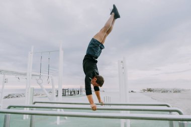 Sportive and athletic man doing functional training exercise at the outdoor gym - Adult athlete doing workout at sunrise at calisthenics park on the beach - Fitness, healthy lifestyle and sport concepts