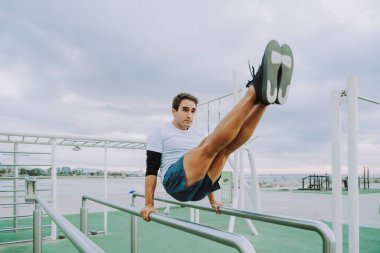 Sportive and athletic man doing functional training exercise at the outdoor gym - Adult athlete doing workout at sunrise at calisthenics park on the beach - Fitness, healthy lifestyle and sport concepts