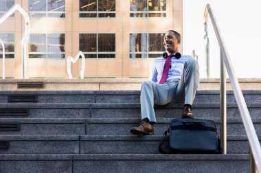 Handsome male african american business man CEO in a stylish corporate elegant suit in a business center outdoors - Black male commuter going to work, city and financial district in the background