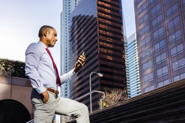 Handsome male african american business man CEO in a stylish corporate elegant suit in a business center outdoors - Black male commuter going to work, city and financial district in the background